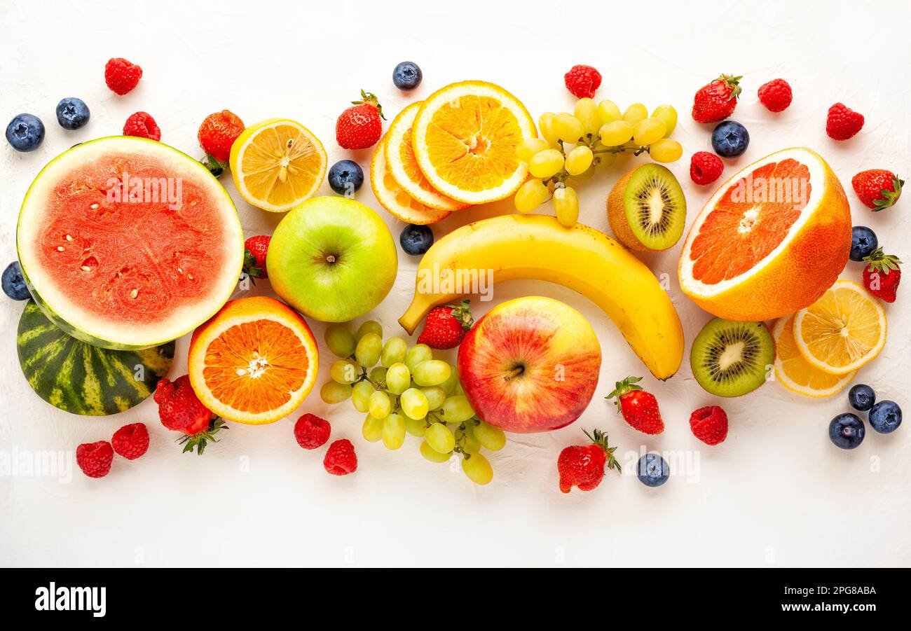 Frutta fresca e frutti di bosco assortiti su sfondo bianco. Mangiare pulito, vita sana. Vista dall'alto. Foto Stock