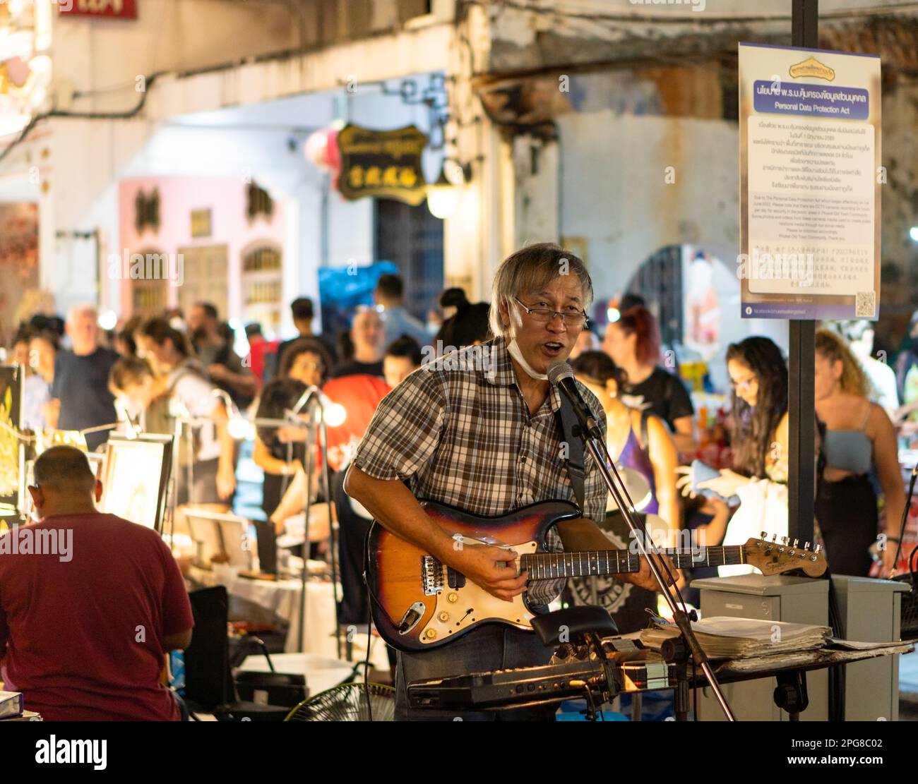 Un musicista che suona la chitarra al mercato del cibo di strada tailandese, nella città vecchia, Phuket, Thailandia Foto Stock