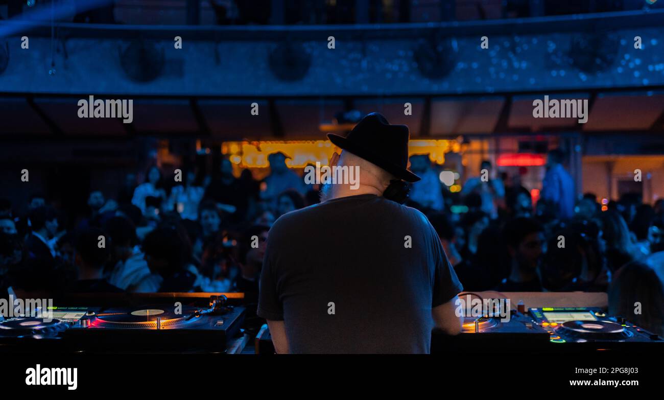 Vista posteriore di un deejay mentre mixa le sue tracce alla console durante un concerto in discoteca Foto Stock