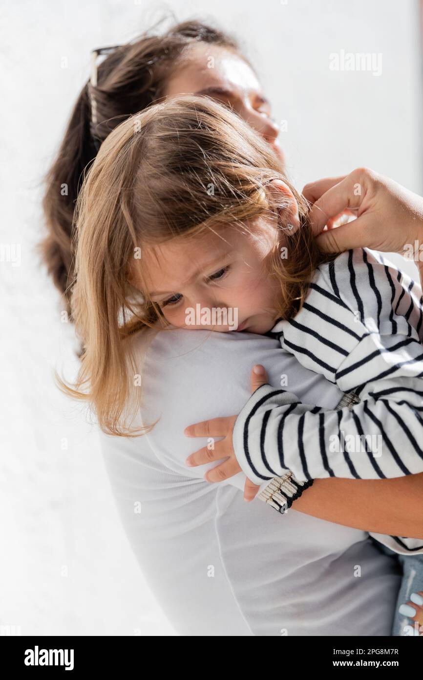 madre premurosa ragazza bambino confortante in camicia manica lunga a righe, immagine stock Foto Stock