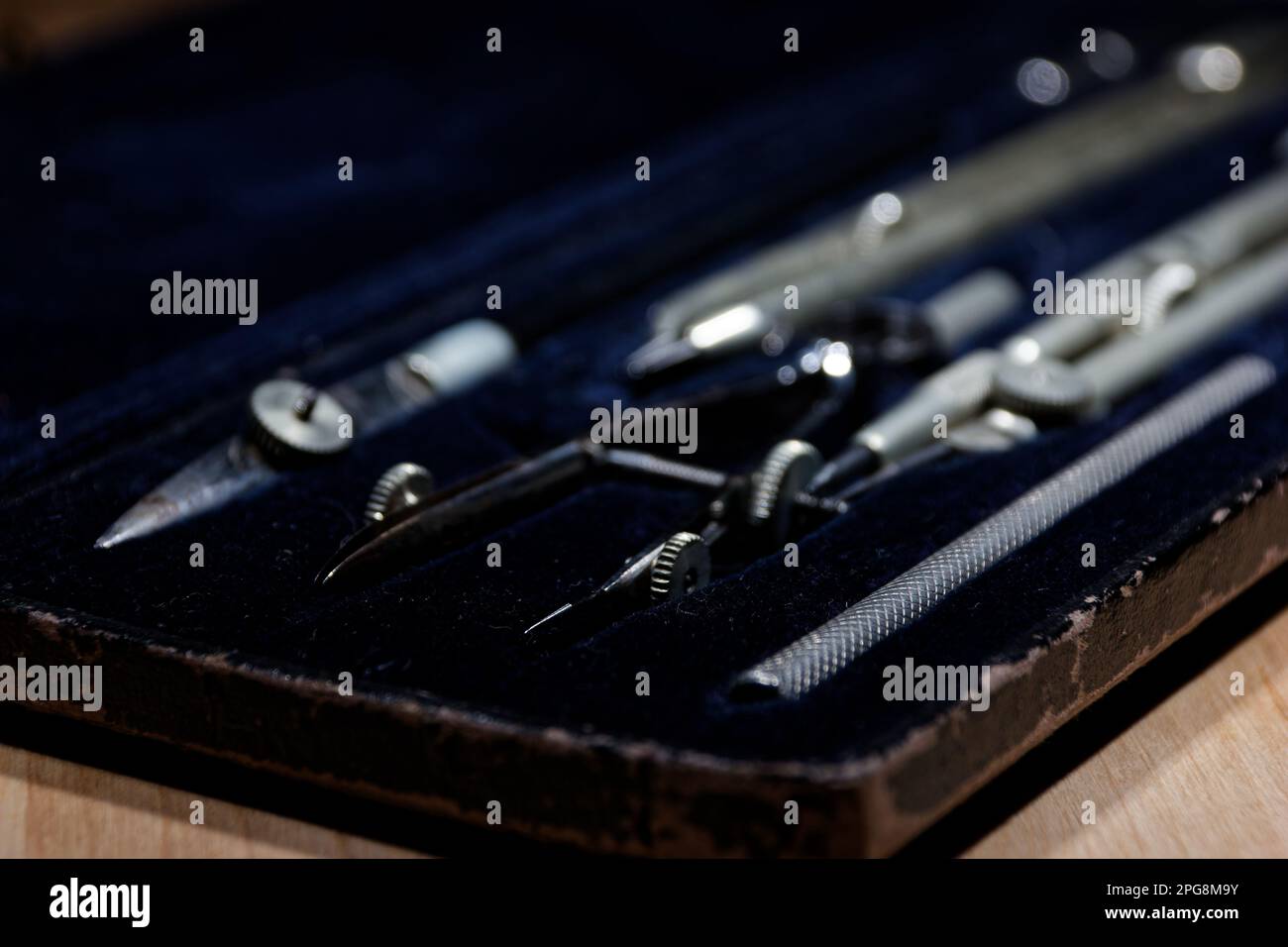 set di divisori, compasso all'interno di una scatola per la costruzione geometrica sdraiata su un tavolo di legno Foto Stock