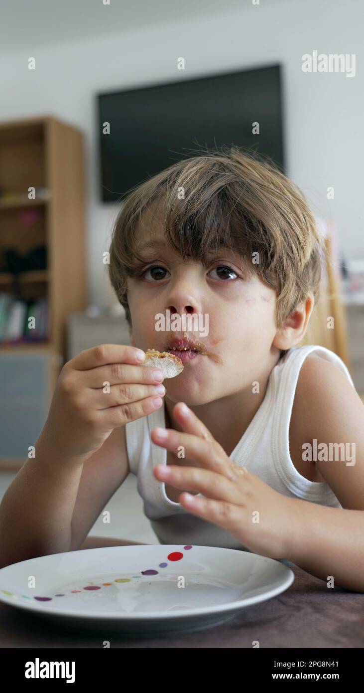 Un ragazzino che mangia pane con burro di arachidi. Ritratto di un bambino  che prende un