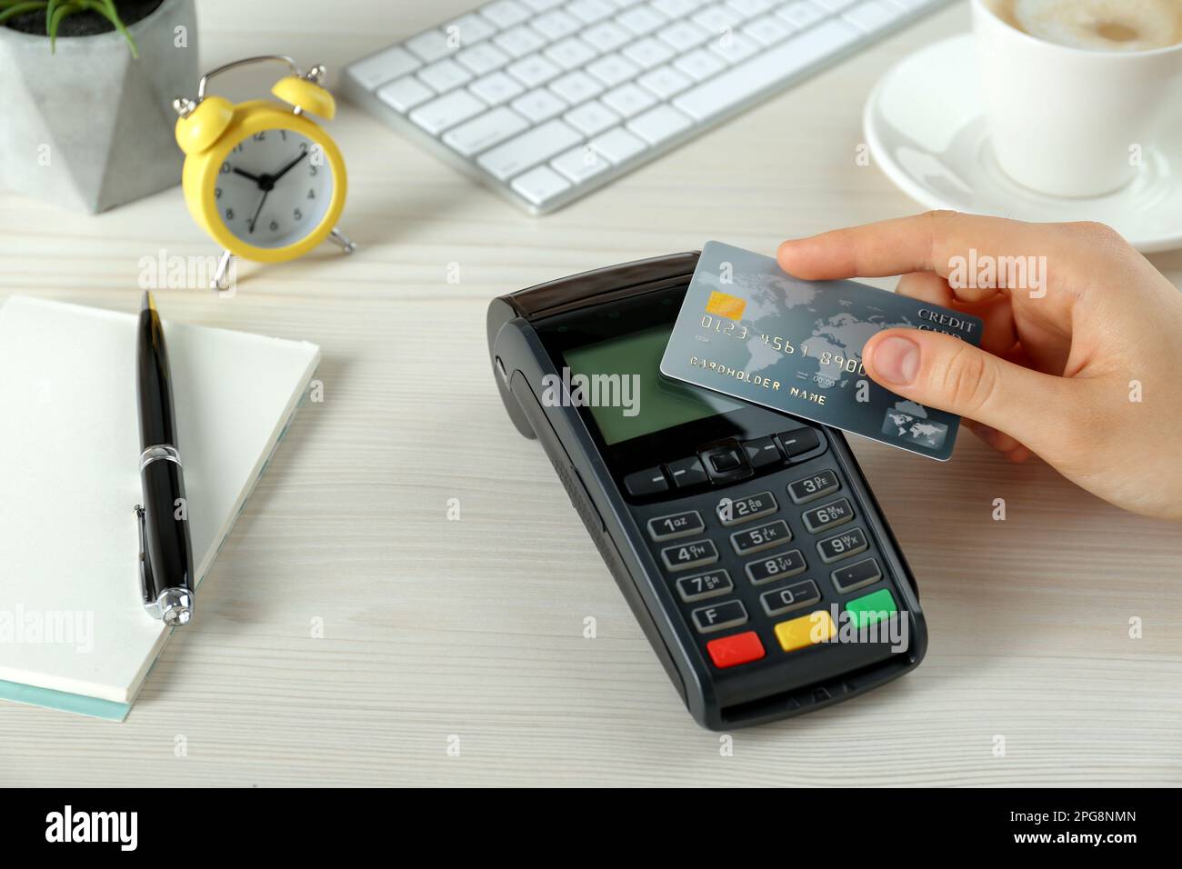 Donna con carta di credito che utilizza un moderno terminale di pagamento al tavolo bianco, primo piano Foto Stock