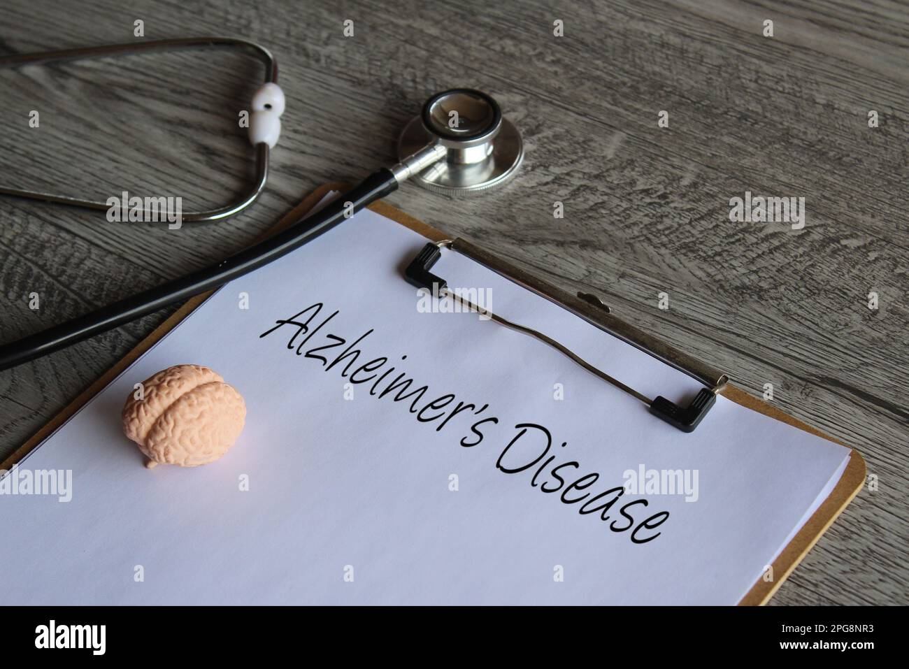 Stetoscopio, modello cerebrale umano e appunti di carta con testo morbo di Alzheimer. Concetto medico e sanitario Foto Stock