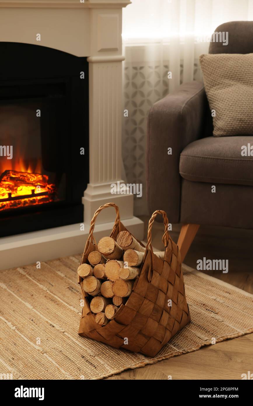 Cestino di vimini con legno vicino al caminetto in camera Foto stock - Alamy