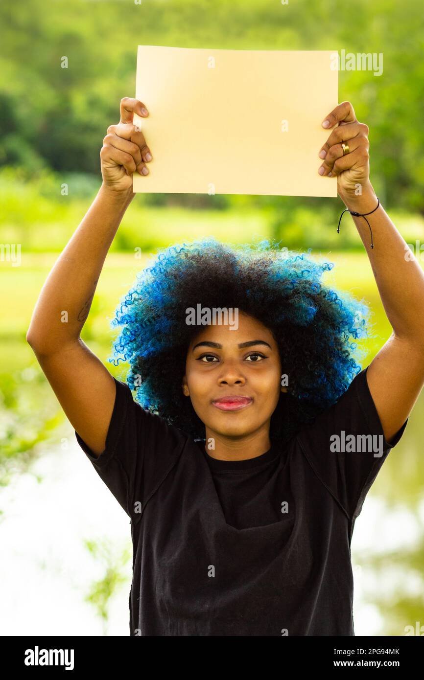 Goiania, Goias, Brasile – 21 marzo 2023: Una giovane donna, con i capelli tinti blu, con un segno bianco, con un paesaggio sullo sfondo. Foto Stock