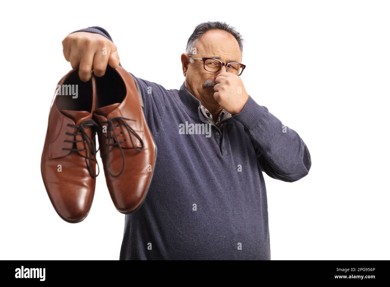 Uomo maturo che tiene un paio di scarpe stinky isolato su sfondo bianco Foto Stock