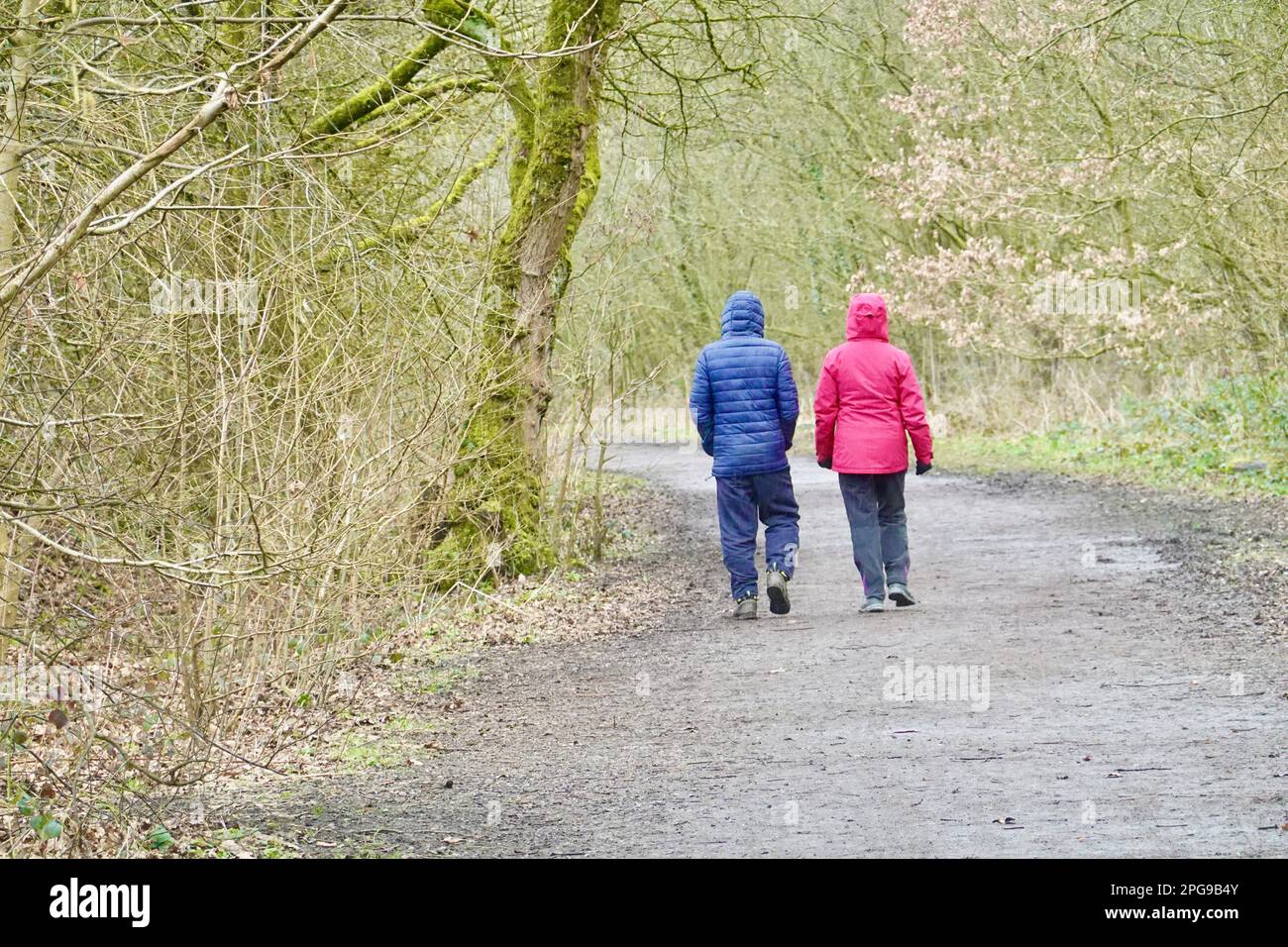 Due persone, una in rosso, l'altra in blu camminano lungo il Sentiero della Sett Valley, Derbyshire Foto Stock