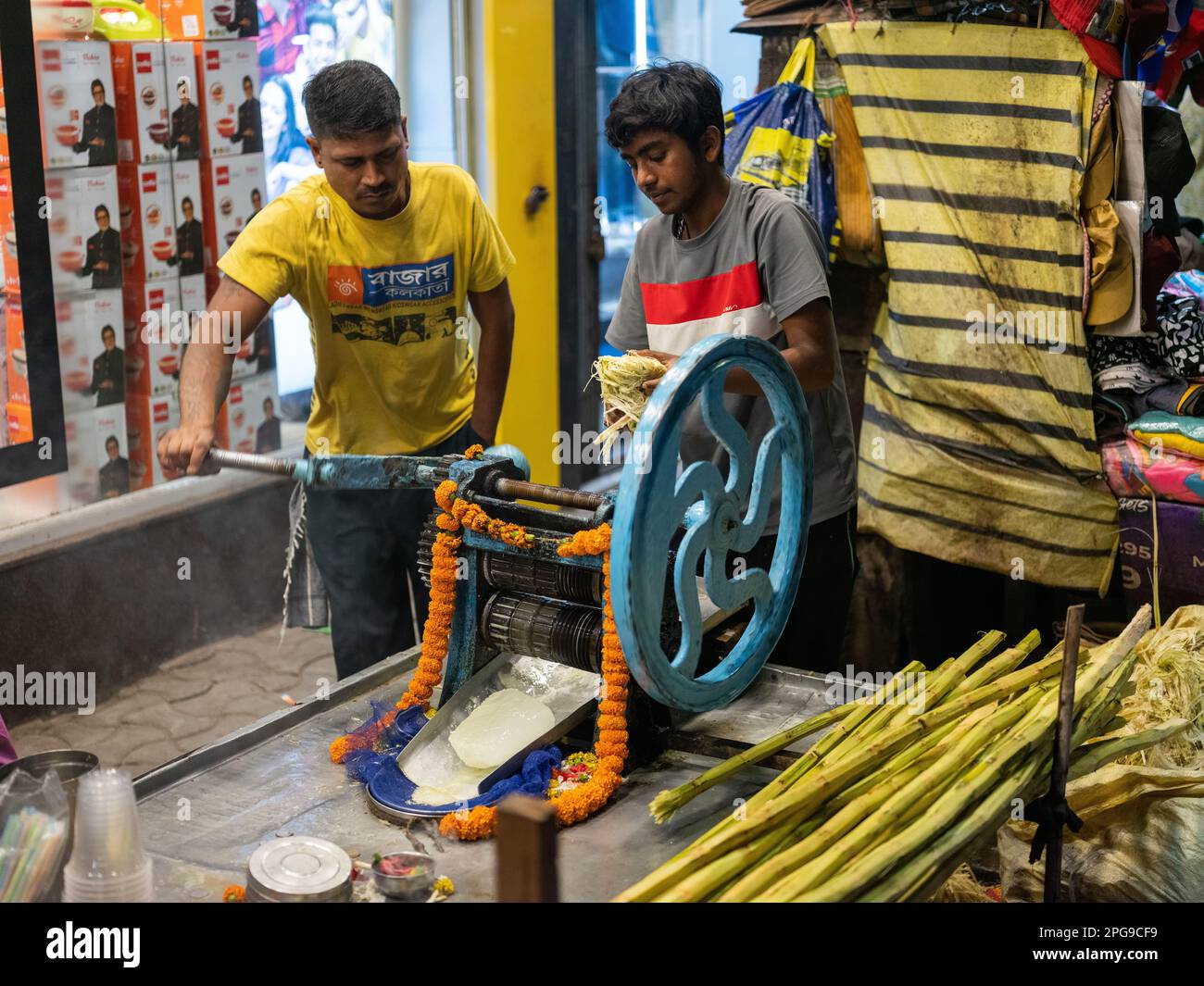 Fare il succo di canna da zucchero nella zona del nuovo mercato di Kolkata, India. Foto Stock