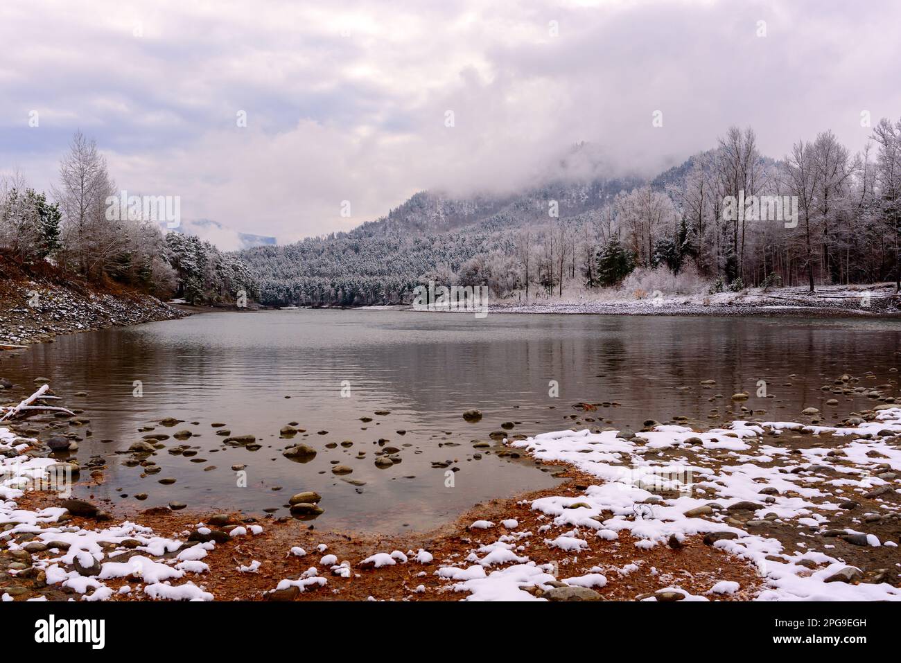 La neve bianca si trova sulla pittoresca spiaggia di pietra vicino alla foresta, vicino alla baia del fiume Katun, sulle montagne Altai in Siberia. Foto Stock