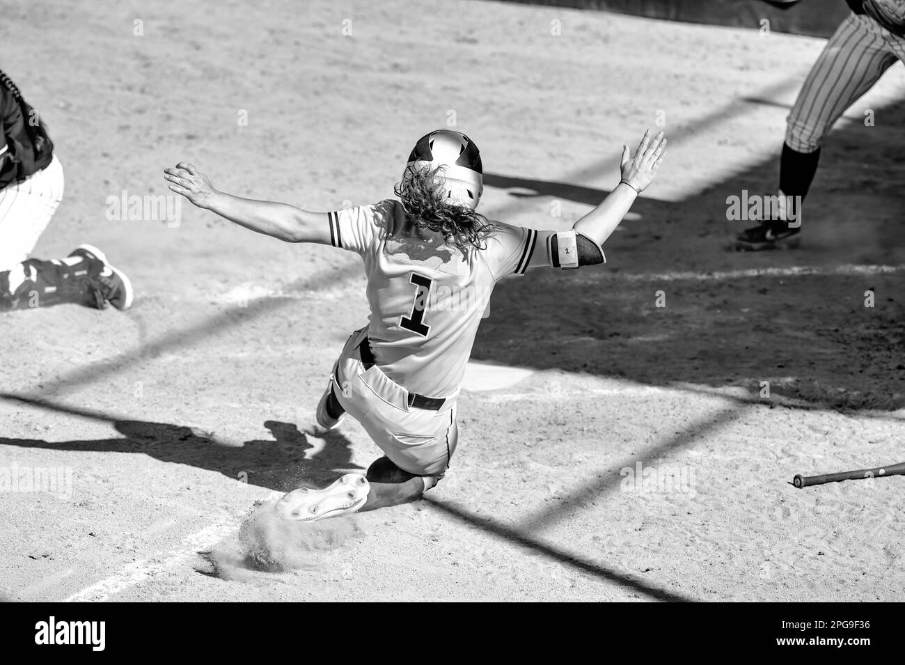 Un giocatore di softball femminile sta scivolando nel piatto principale Foto Stock