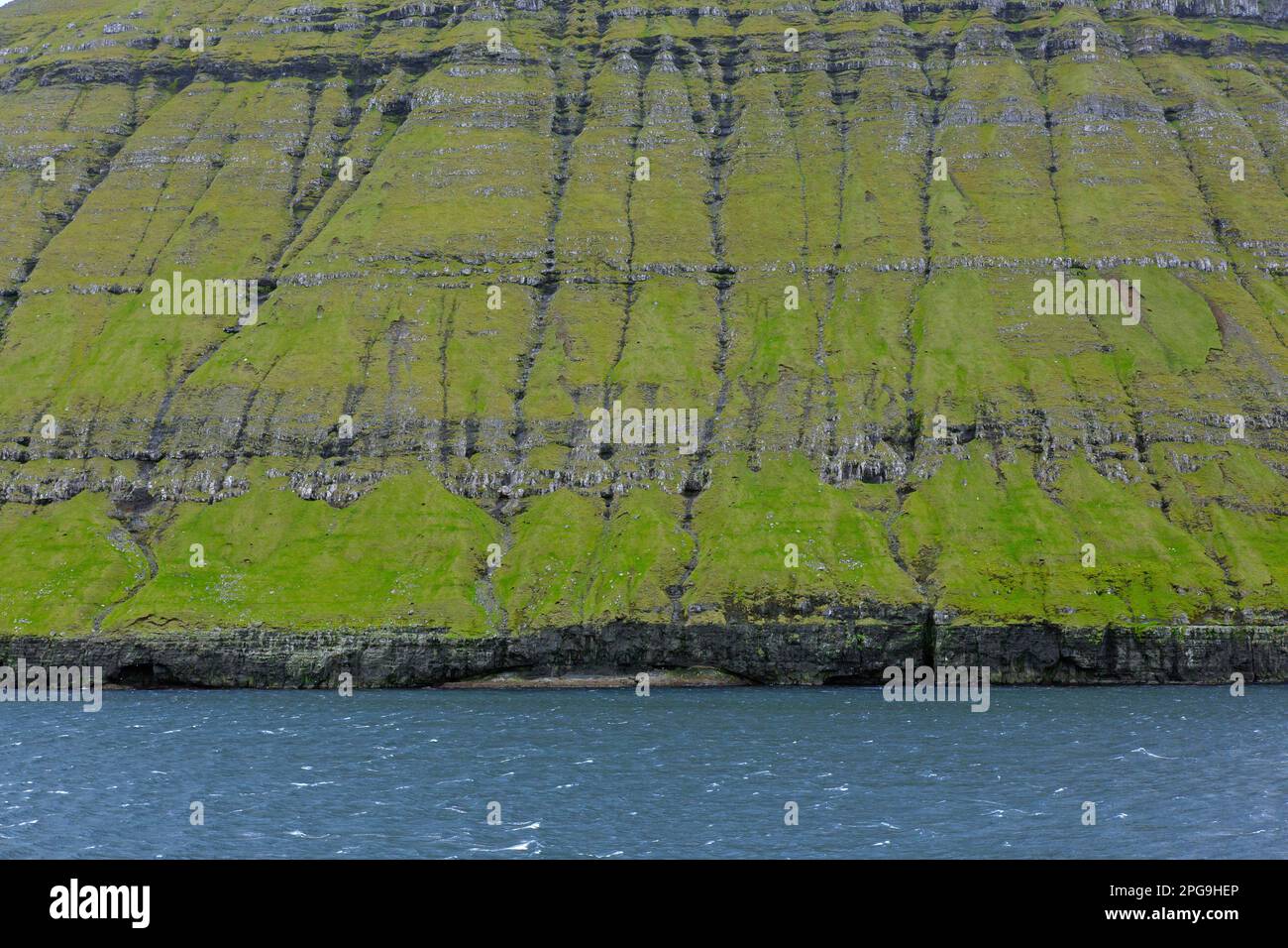 Scogliere sul mare lungo la costa frastagliata di Eysturoy / Isola Est, regione e seconda più grande delle Isole Faroe / Faroes nel Nord Atlantico Foto Stock