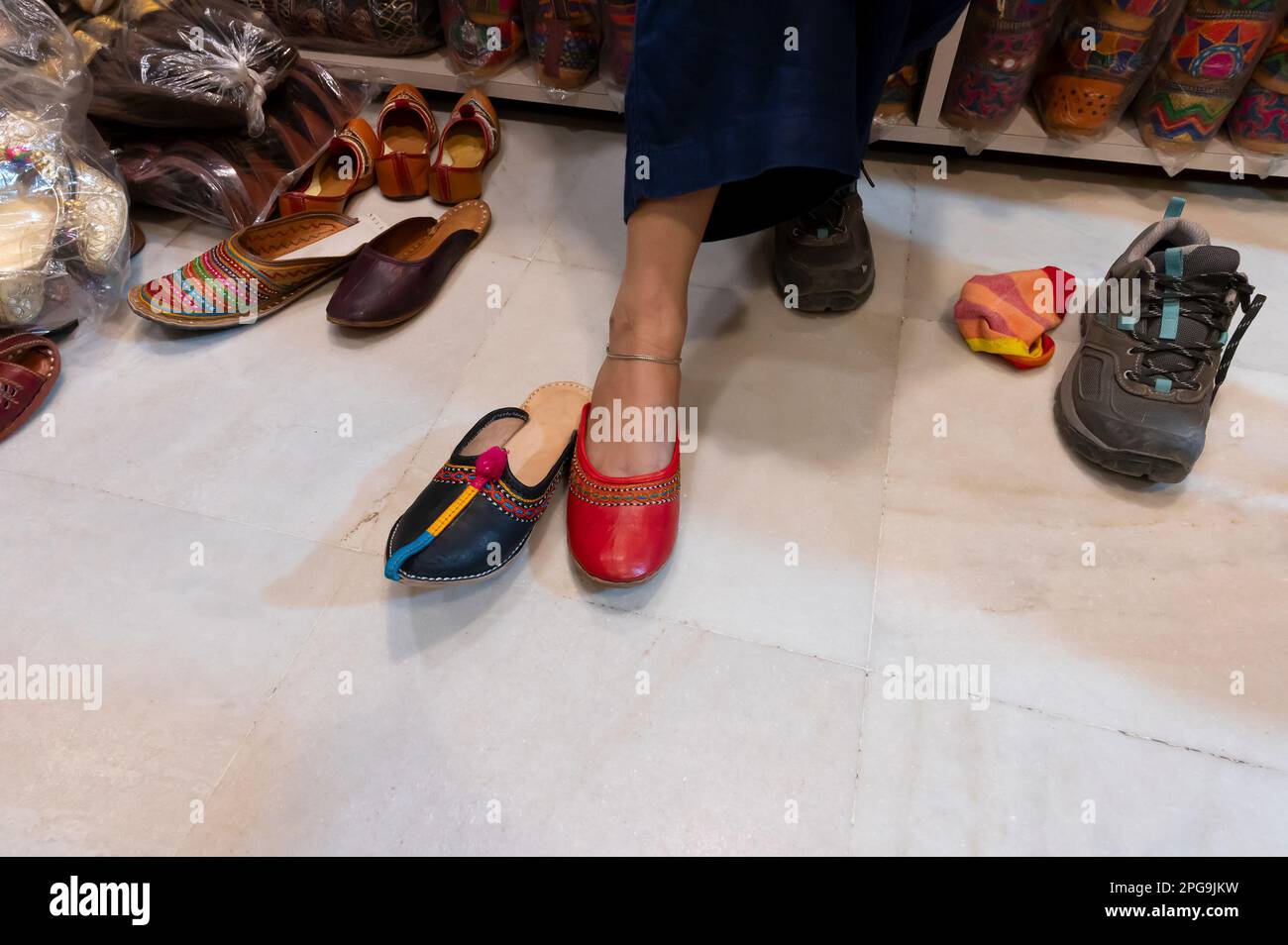 Bella donna indiana che prova il suo piede per il montaggio di colorate scarpe da donna Rajsathani al negozio di scarpe al famoso mercato Sardar e Ghanta ghar. Foto Stock