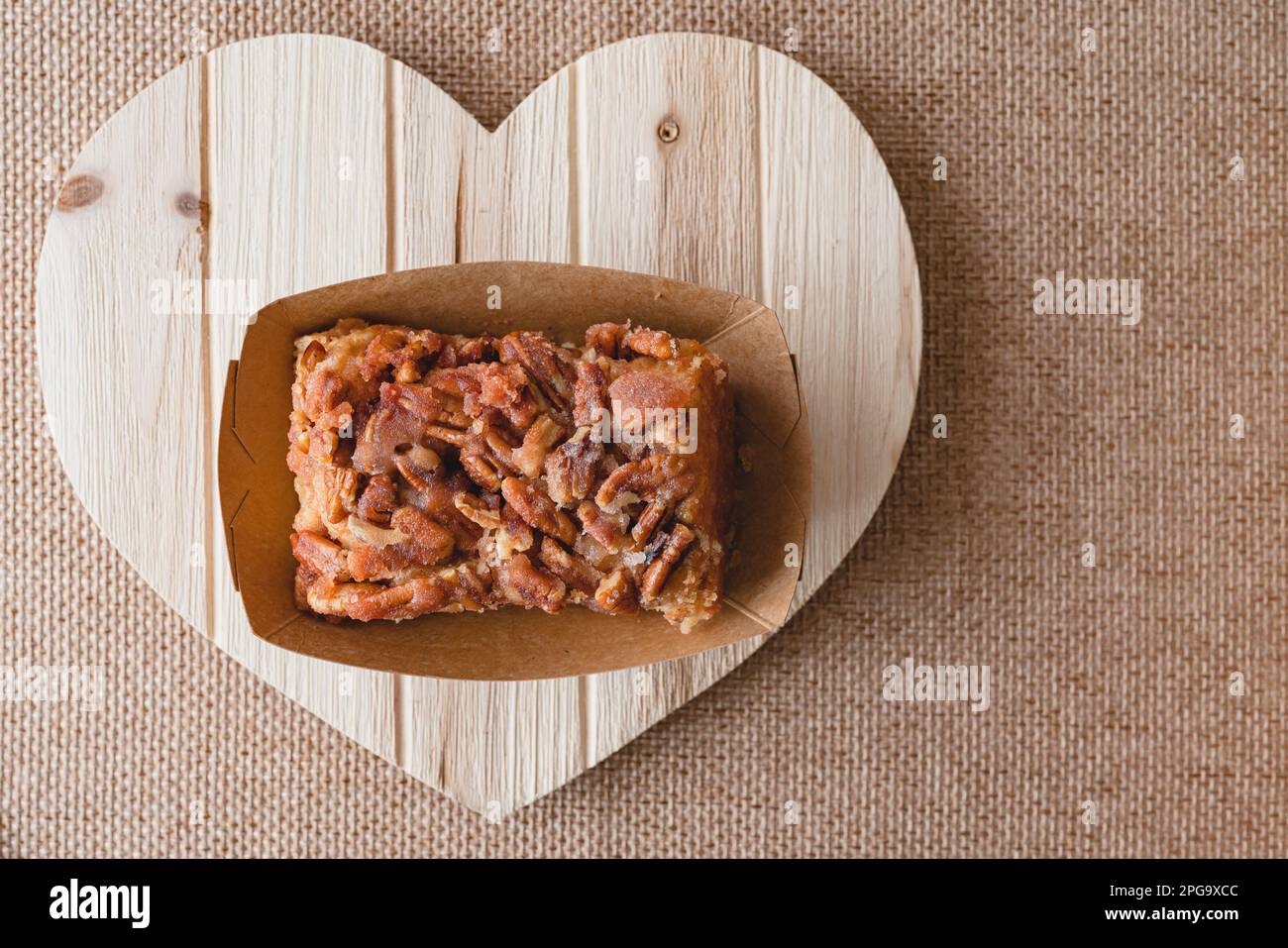 Rotolo di cannella di Pecan vicino su un bordo di legno a forma di cuore, giacitura piatta con spazio di copia Foto Stock