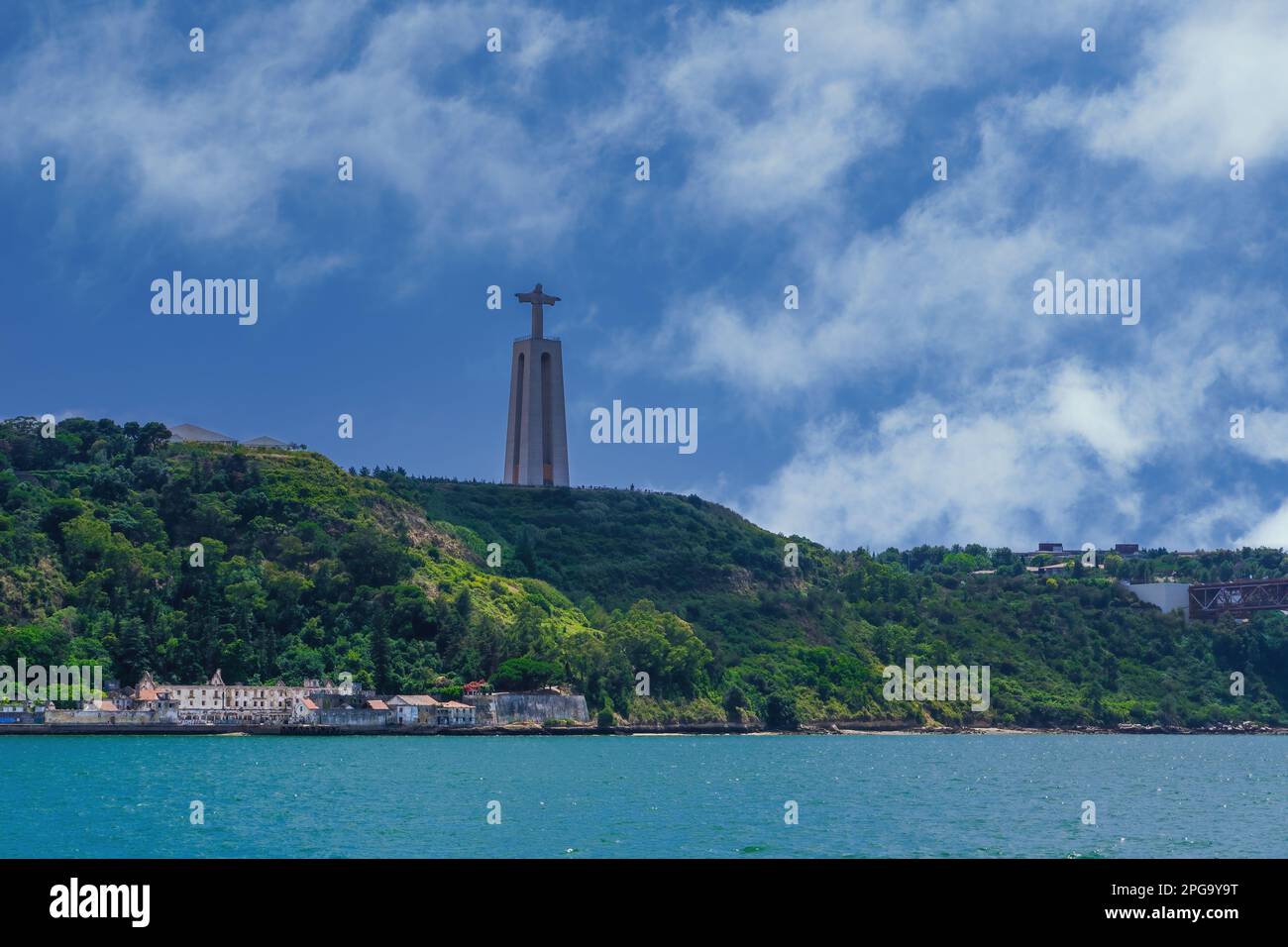 Lisbona, Portogallo giorno vista mare della statua di Cristo Rei, Santuario di Cristo Re, contro il cielo blu con le nuvole sul fiume Tago. Foto Stock