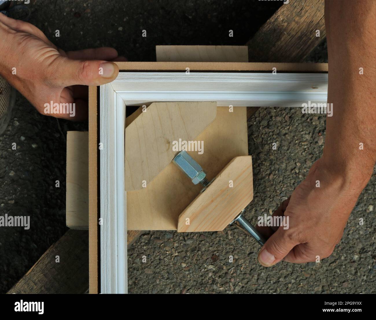 serraggio delle tavole di un telaio di porte di legno chiaro e creazione di un angolo retto nella struttura utilizzando un dispositivo fatto in casa, formando l'angolo desiderato Foto Stock