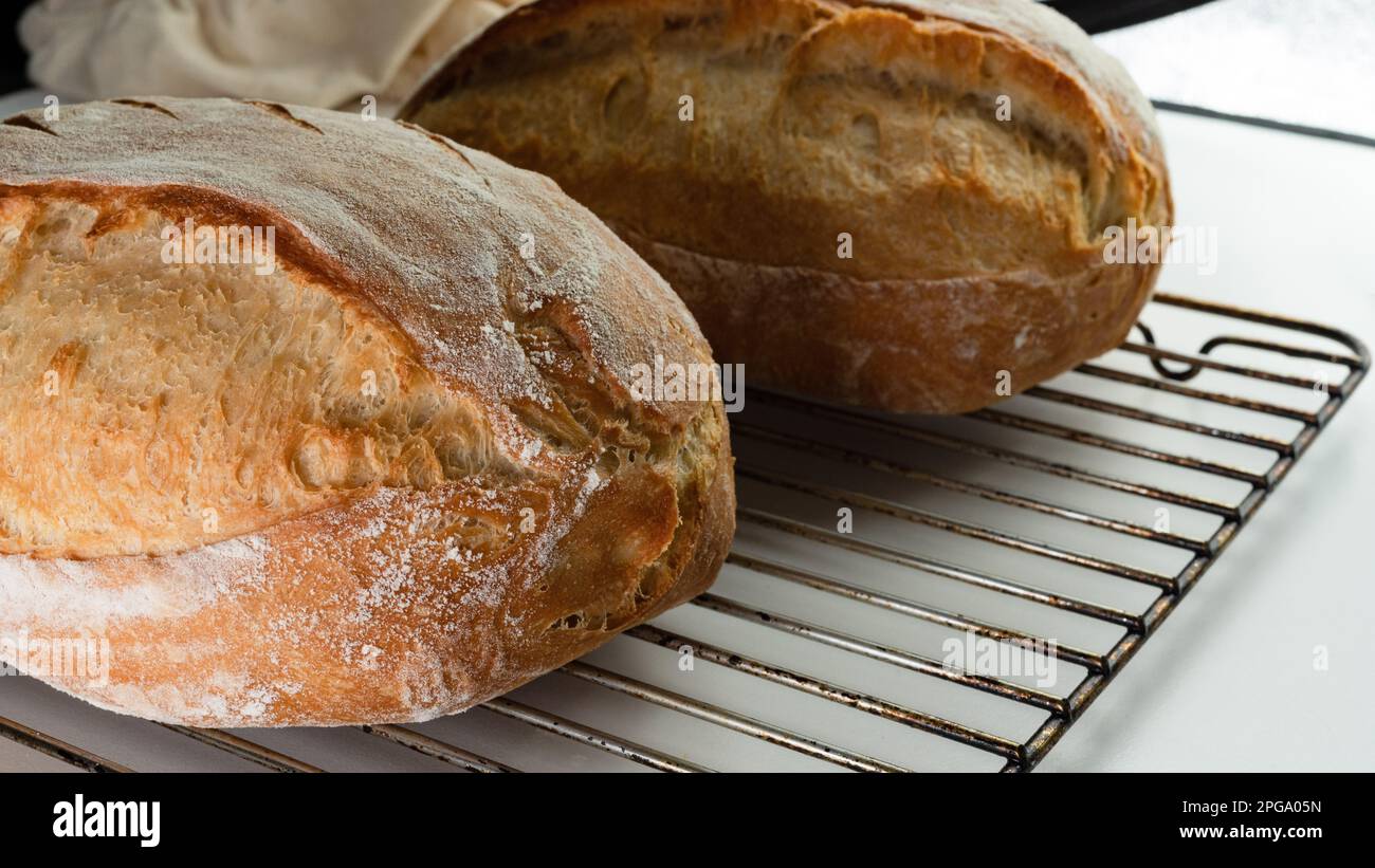 Pane croccante fatto a mano su una griglia di raffreddamento in metallo, due viste laterali ravvicinate del pane rustico. Foto Stock