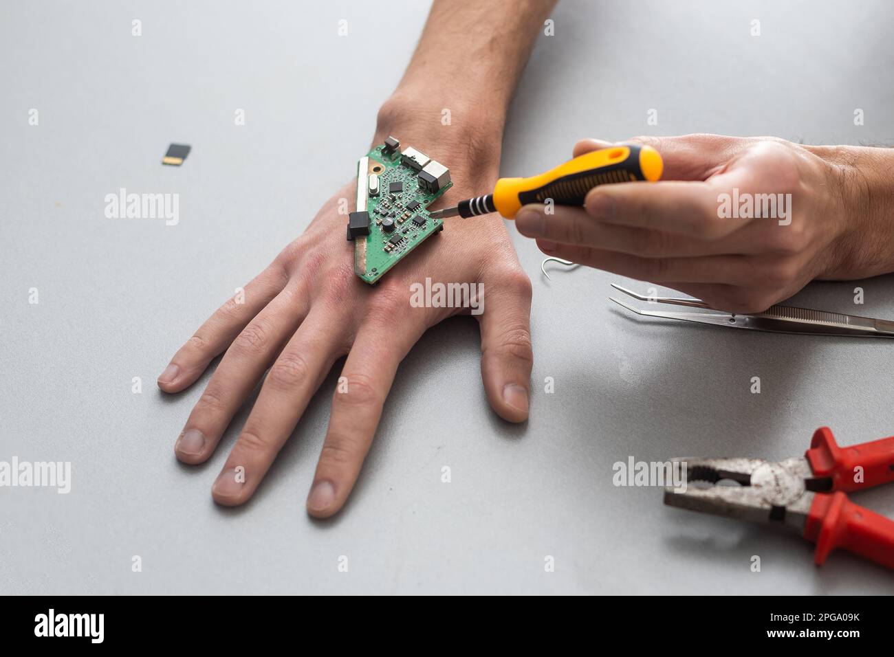 Concetto del braccio del robot. L'uomo mostra una mano biomeccanica protesica. Guy ripara la mano con l'attrezzo. Bioingegneria, transumanesimo, biohacking, cyborg umano Foto Stock