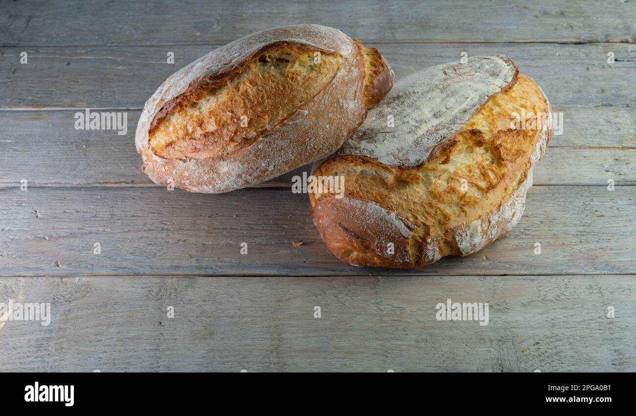 Pane casereccio croccante su asse di legno a base di lievito e farina bianca forte biologica, yogurt, miele e acqua. Foto Stock