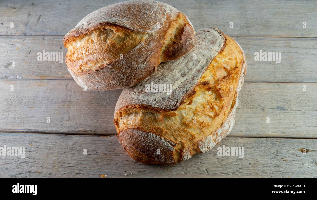 Pane casereccio croccante su asse di legno a base di lievito e farina bianca forte biologica, yogurt, miele e acqua. Foto Stock