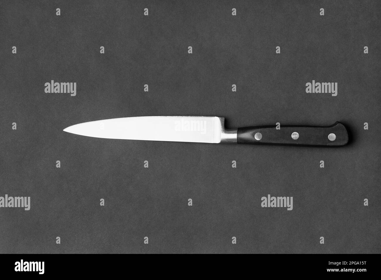 Coltello da cucina con manico nero su sfondo nero. Coltello grande su sfondo scuro. Utensili da cucina. Coltello con lama larga. Foto Stock