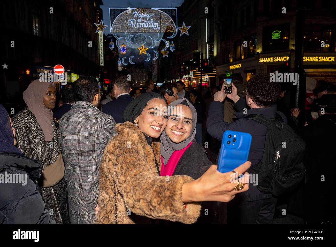 Londra, Regno Unito. 21 marzo 2023. I visitatori prendono un selfie contro la prima installazione di luci Ramadan che si accende a Piccadilly Circus alla vigilia della prima giornata del Ramadan 2023. Luci di questa scala sono le prime nel Regno Unito e in Europa, con 30.000 luci sostenibili illuminate nel centro di Londra per tutto il mese di Ramadan. Credit: Stephen Chung / Alamy Live News Foto Stock