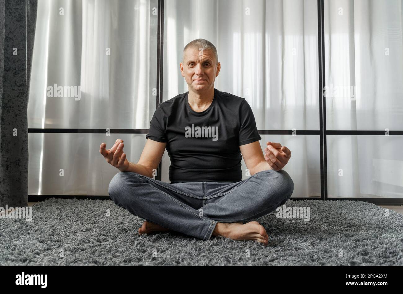 Il concetto di uno stile di vita sano. Ritratto di un uomo che medita in posizione loto su un tappetino yoga durante una pausa al lavoro. Foto Stock