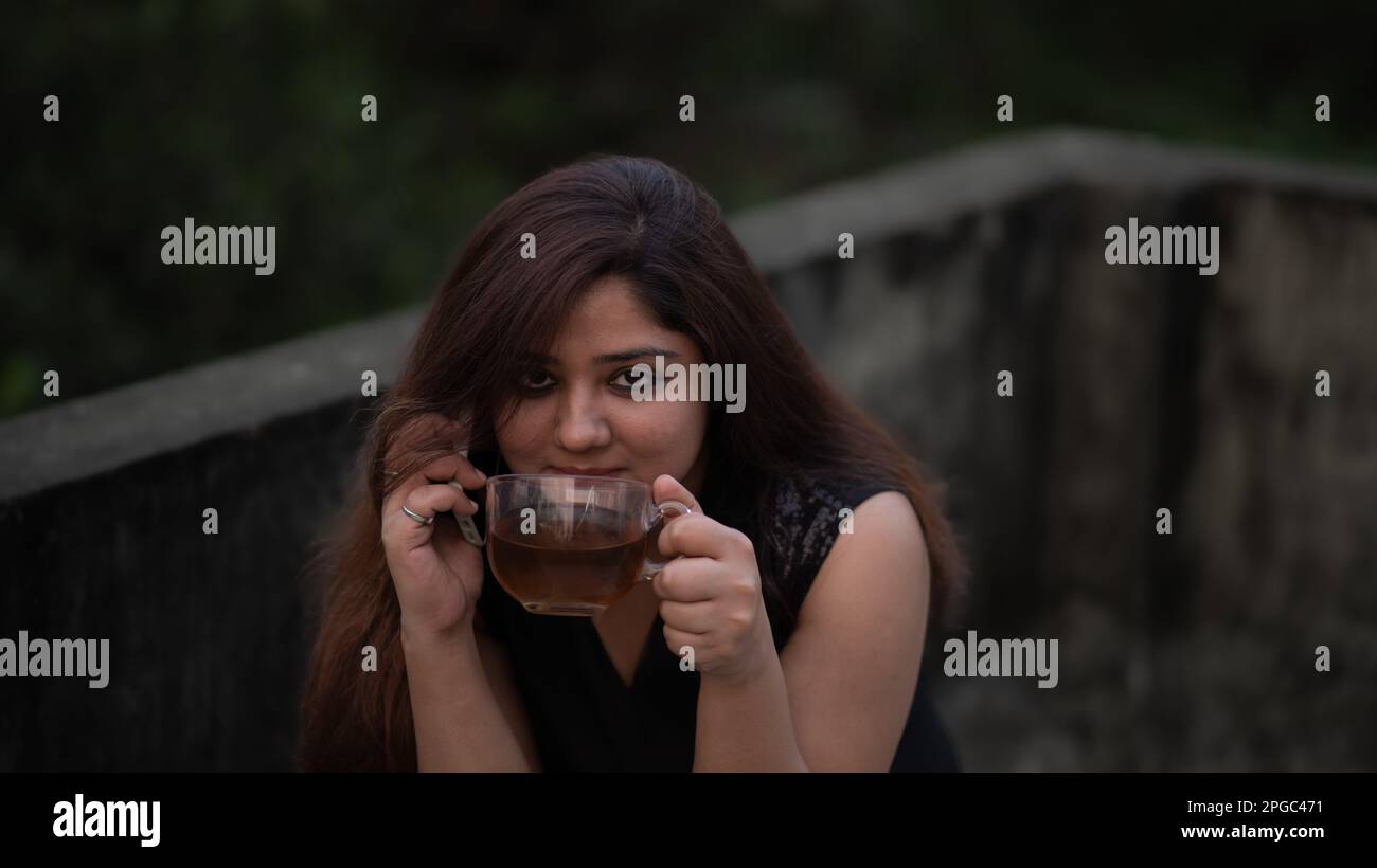 Donne che si siedono tenendo il telefono cellulare parlare bere tè nero Foto Stock