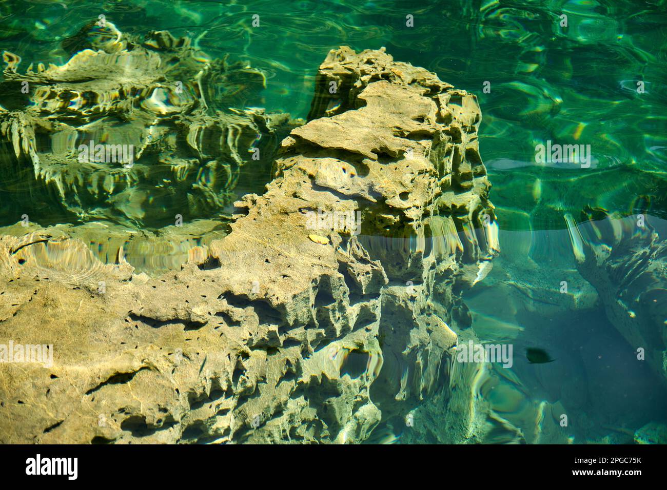 Una roccia grezza appena sotto il livello dell'acqua in Coron, Palawan nelle Filippine con l'acqua verde che riflette la luce. Foto Stock