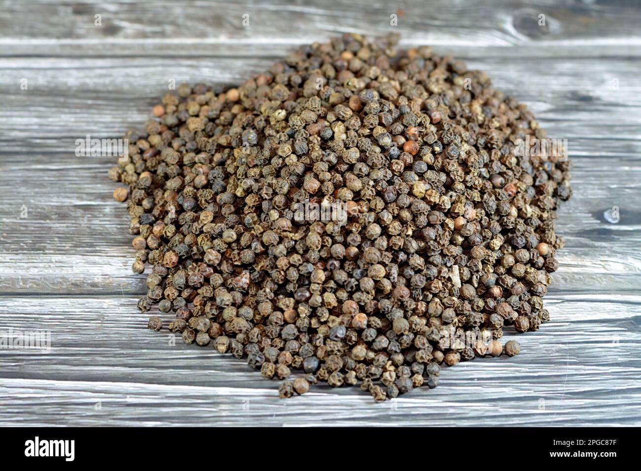 Mucchio di grani di pepe, pepe nero (Piper nigrum), un vitigno fiorito della famiglia Piperaceae, coltivato per il suo frutto il grano di pepe, essiccato e usato un Foto Stock