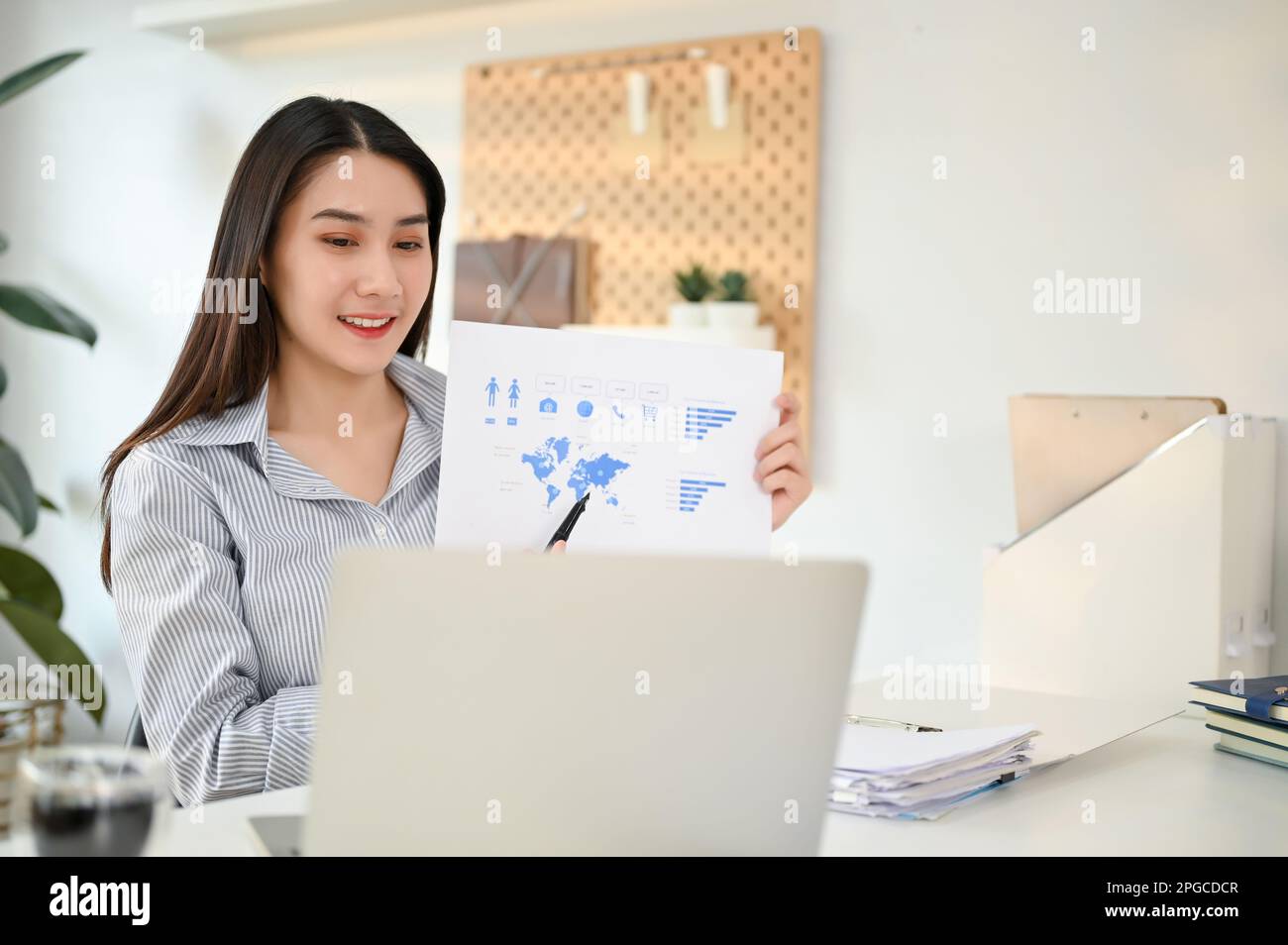 Affascinante e intelligente giovane donna d'affari asiatica o analista di marketing femminile che hanno un incontro online con il suo team di marketing nel suo ufficio. Foto Stock