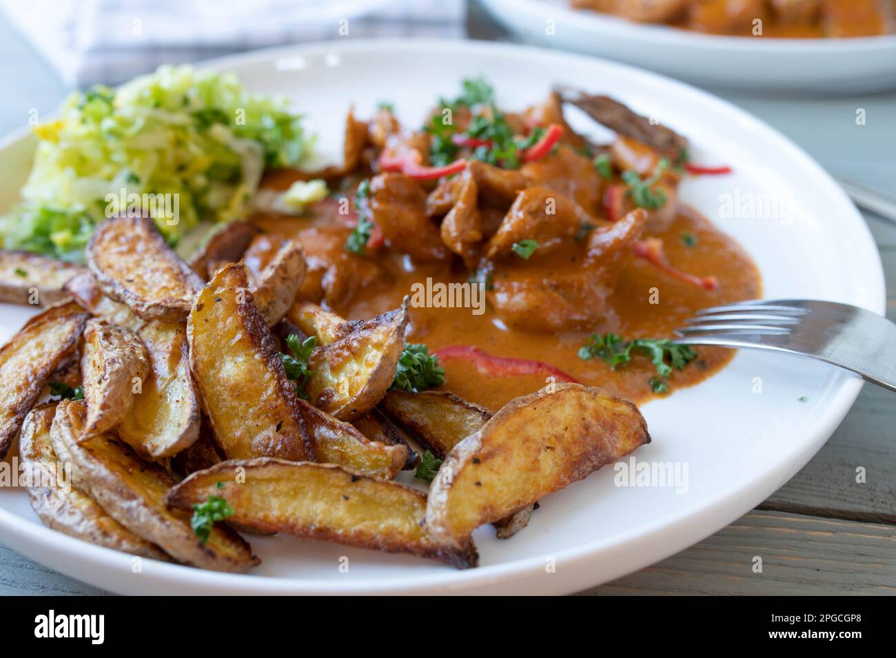 Spicchi di patate con pollo, salsa e insalata su un piatto Foto Stock