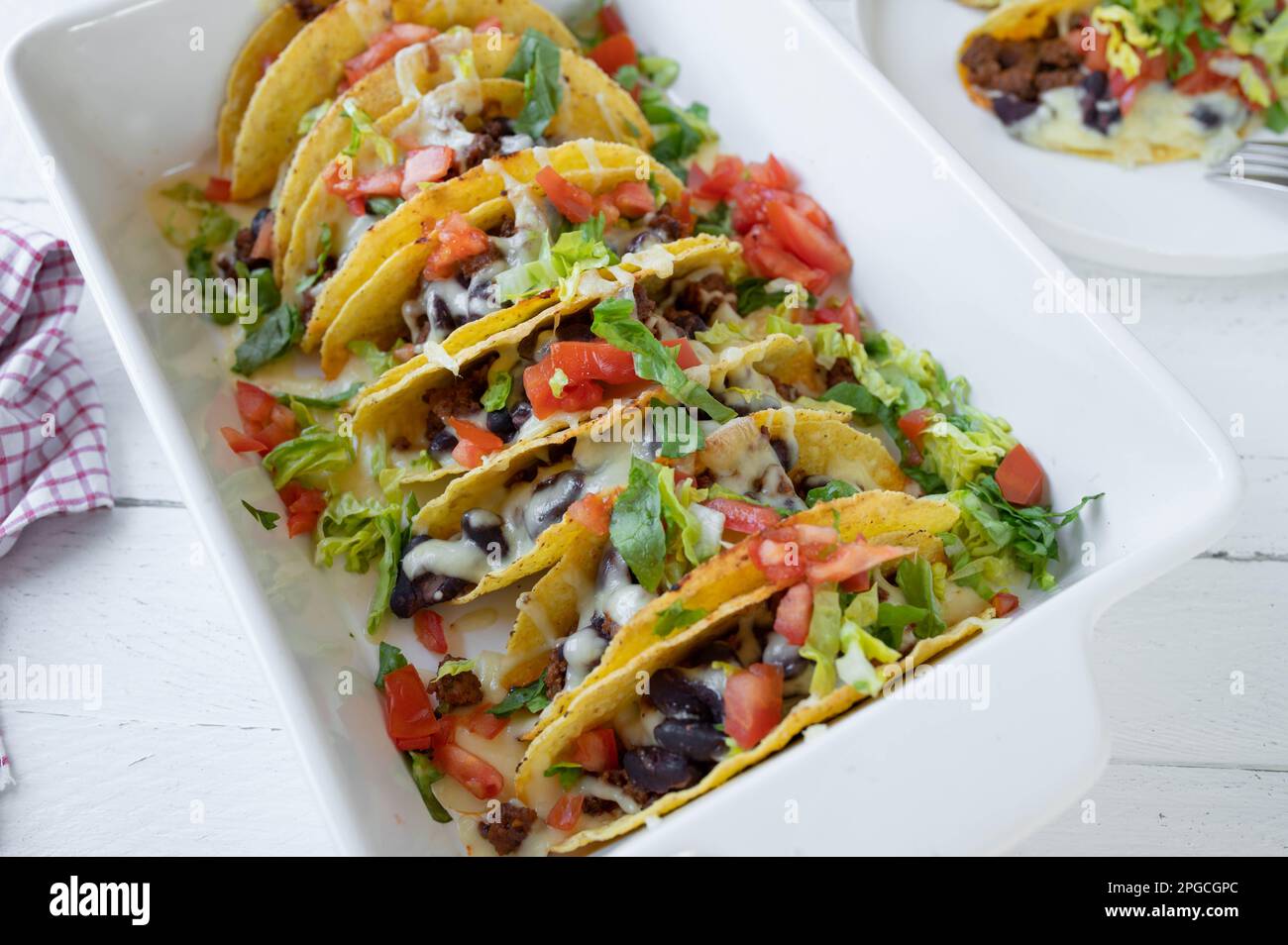 Tacos con carne macinata, fagioli rossi, formaggio, pomodori e lattuga in una casseruola. Tex mex al forno Foto Stock