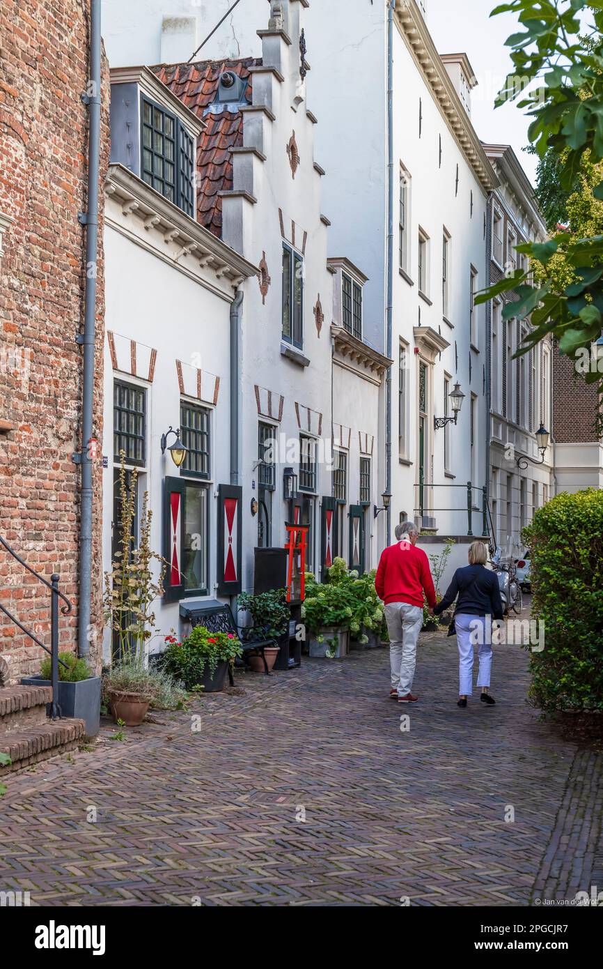 Due anziani camminano mano nella mano attraverso una strada medievale di Amersfoort. Foto Stock