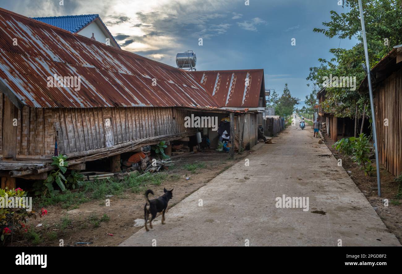 Un vicolo che passa accanto a una tradizionale casa lunga su palafitte che conduce nel villaggio di minoranza etnica Mnong di buon Jun, Lien Son, Vietnam. Foto Stock