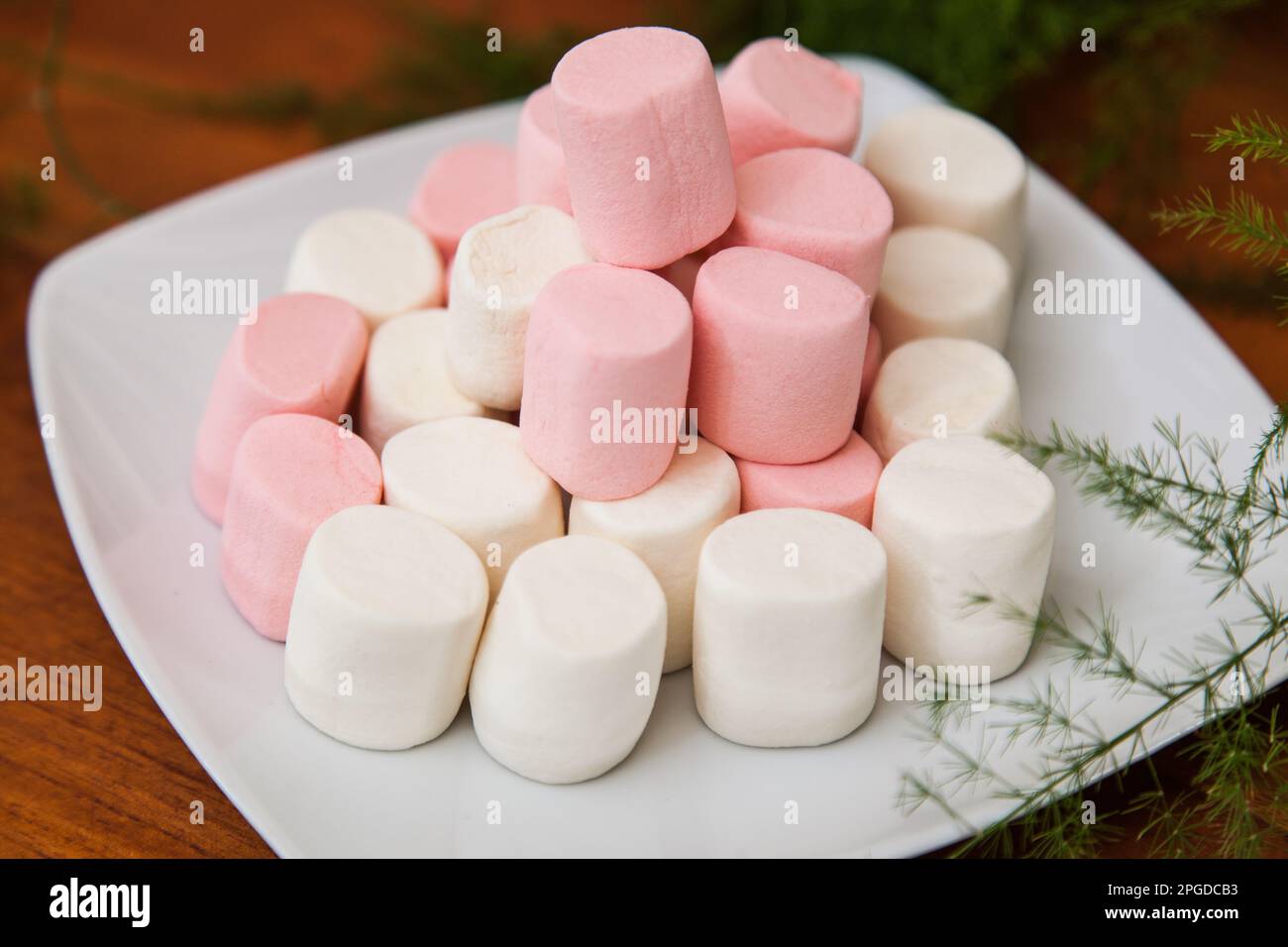 Piatto con marshmallow rosa e bianco su sfondo di legno. Foto Stock