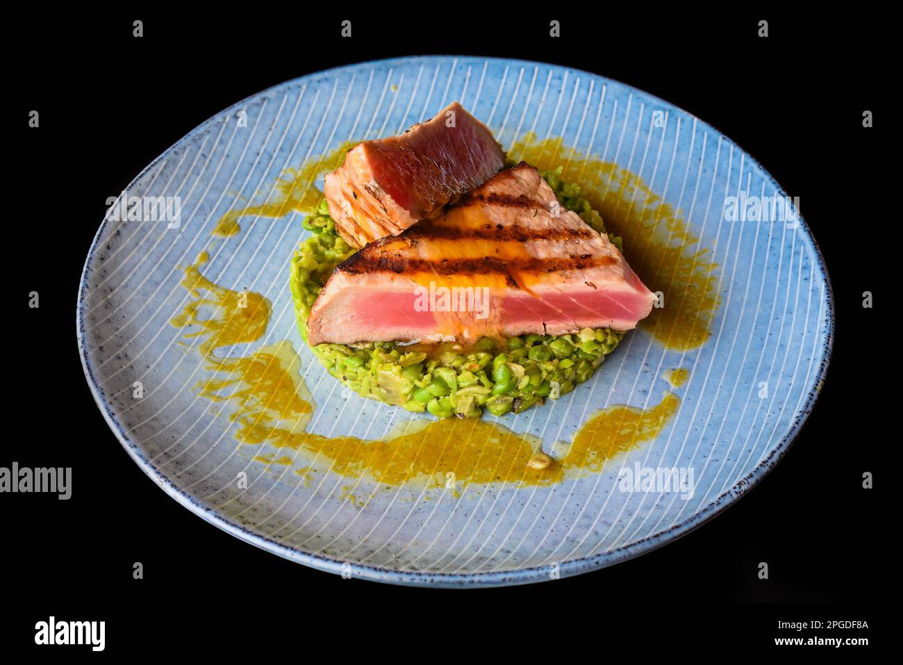 Bistecca di manzo media rara con sangue servito con piselli isolati su sfondo nero vista laterale Foto Stock