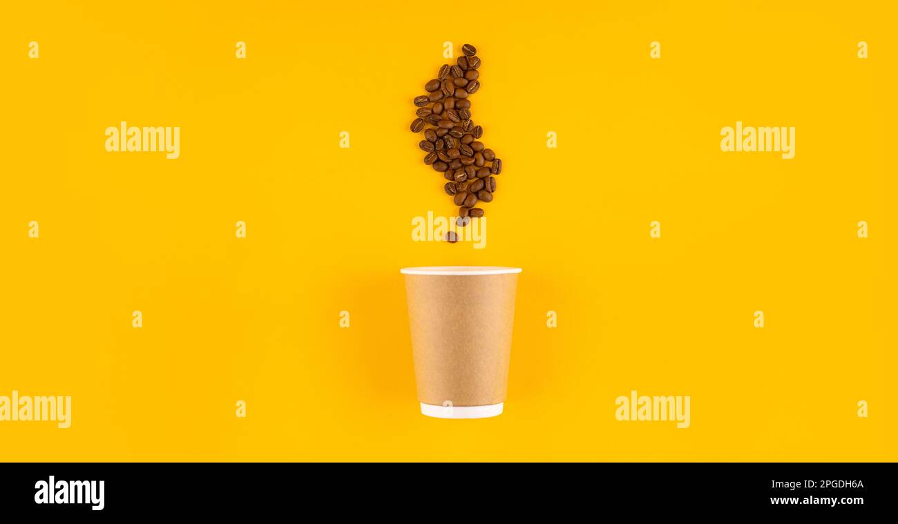 Tazza di caffè in carta con chicchi a forma di vapore. Sfondo giallo. Spazio di copia Foto Stock
