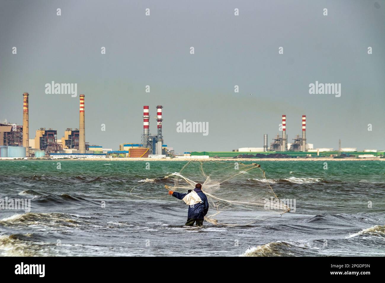 Un pescatore che getta le sue reti nel mare Foto Stock