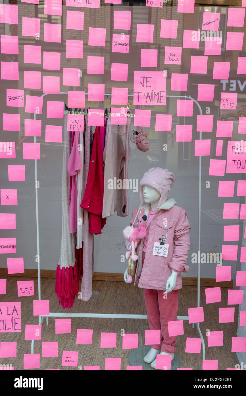 Vetrina di un negozio di abbigliamento coperto di post-it rosa, formando una finestra circolare in cui sono esposti i vestiti rosa. Bruxelles. Foto Stock