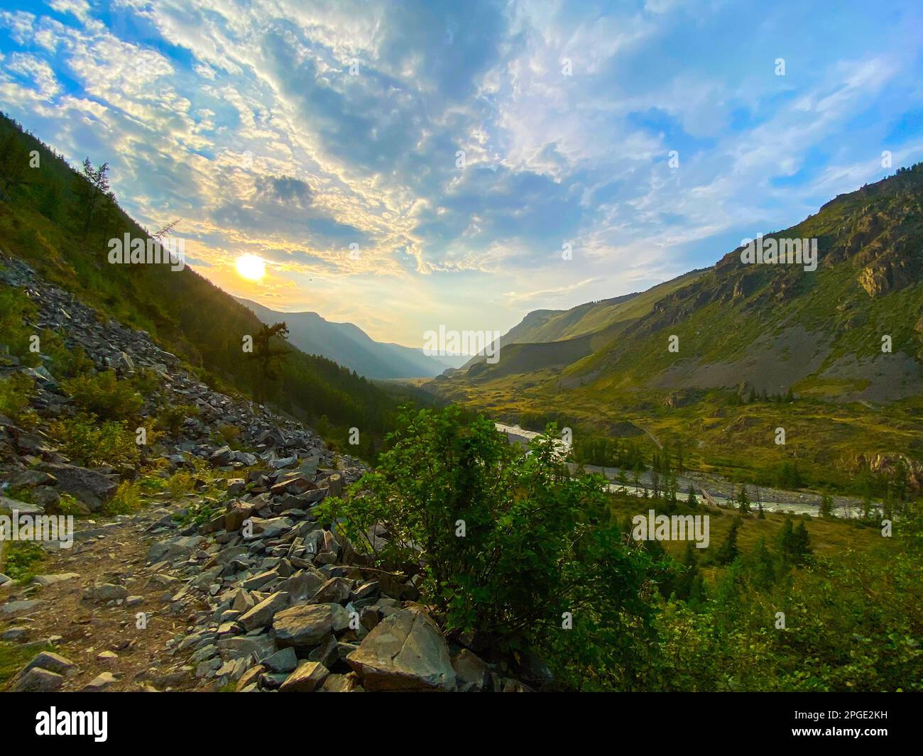 Sentiero lungo la montagna con pietre vicino alla valle sotto la montagna inondato di sole al tramonto con il fiume Chuya sotto la scogliera di pietra sotto Th Foto Stock