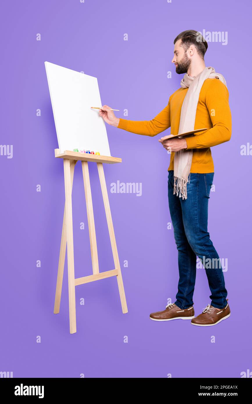 Ritratto integrale di un artista creativo impegnato con sciarpa intorno al collo, acconciatura, in jeans, maglione, con tavolozza colorata e disegno A. Foto Stock
