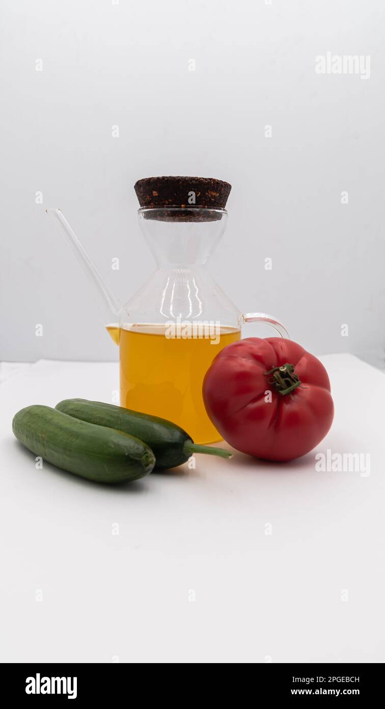 Concetto di cibo sano. Olio d'oliva in bottiglia di vetro e pomodoro e cetrioli su fondo bianco isolato. Foto Stock