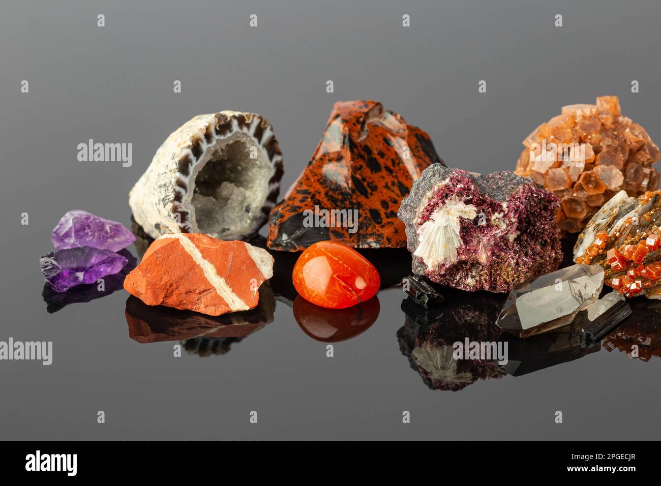 Foto ravvicinata del Gruppo delle pietre e dei minerali, tra cui il gelsomino rosso, l'aragonite Sputnik, i cristalli di Erythrite, l'Obsidiana di Mogano e l'Agata Geode su R Foto Stock