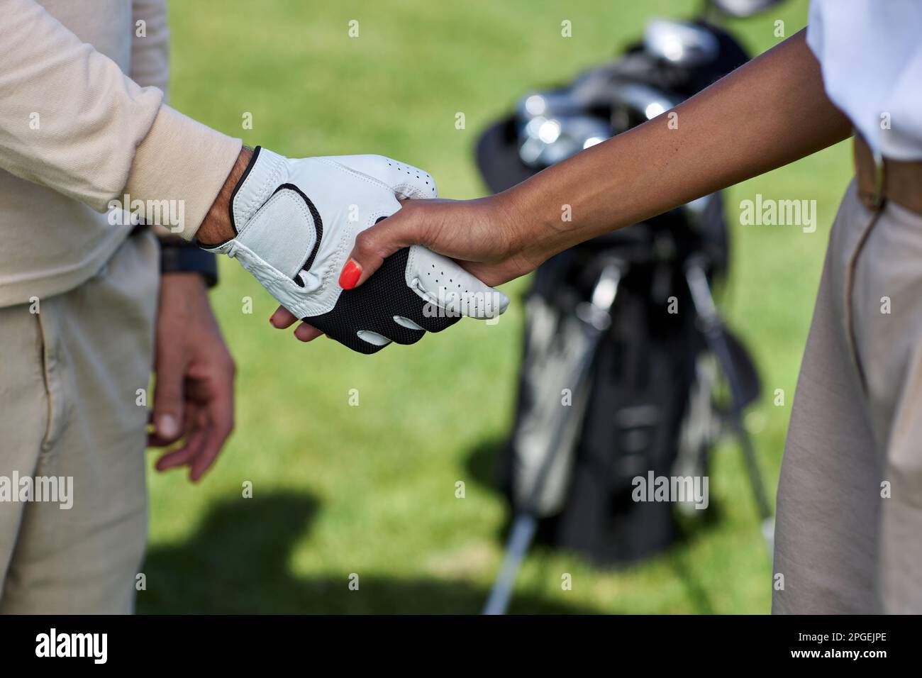 Primo piano di due giocatori di golf che scuotono le mani dopo la partita all'aperto Foto Stock
