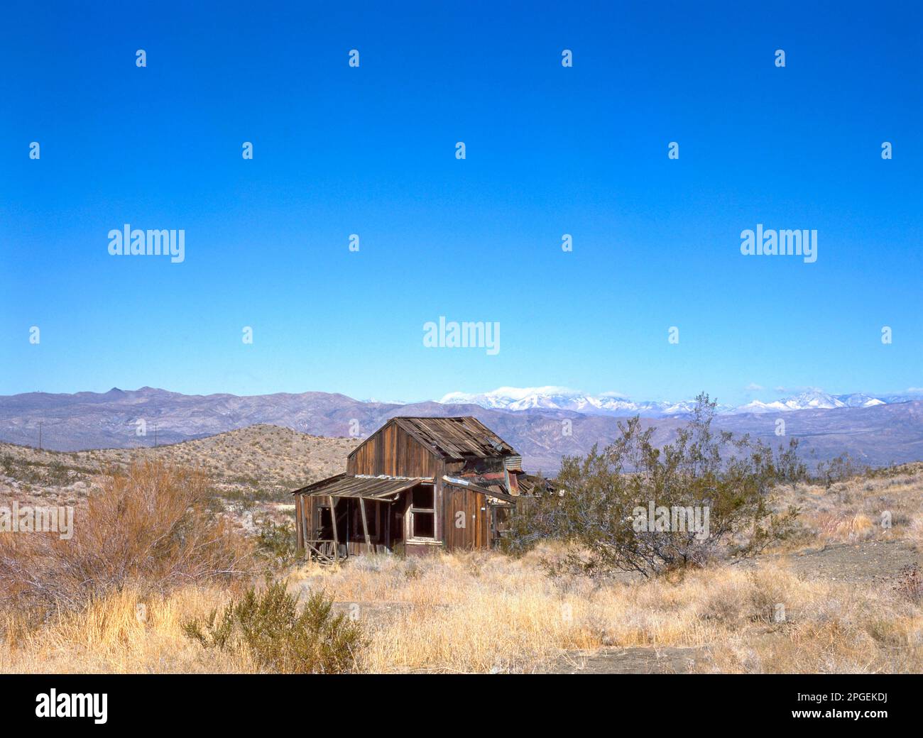 Abbandonata casa di città fantasma di legno nel deserto californiano con montagne sullo sfondo Foto Stock