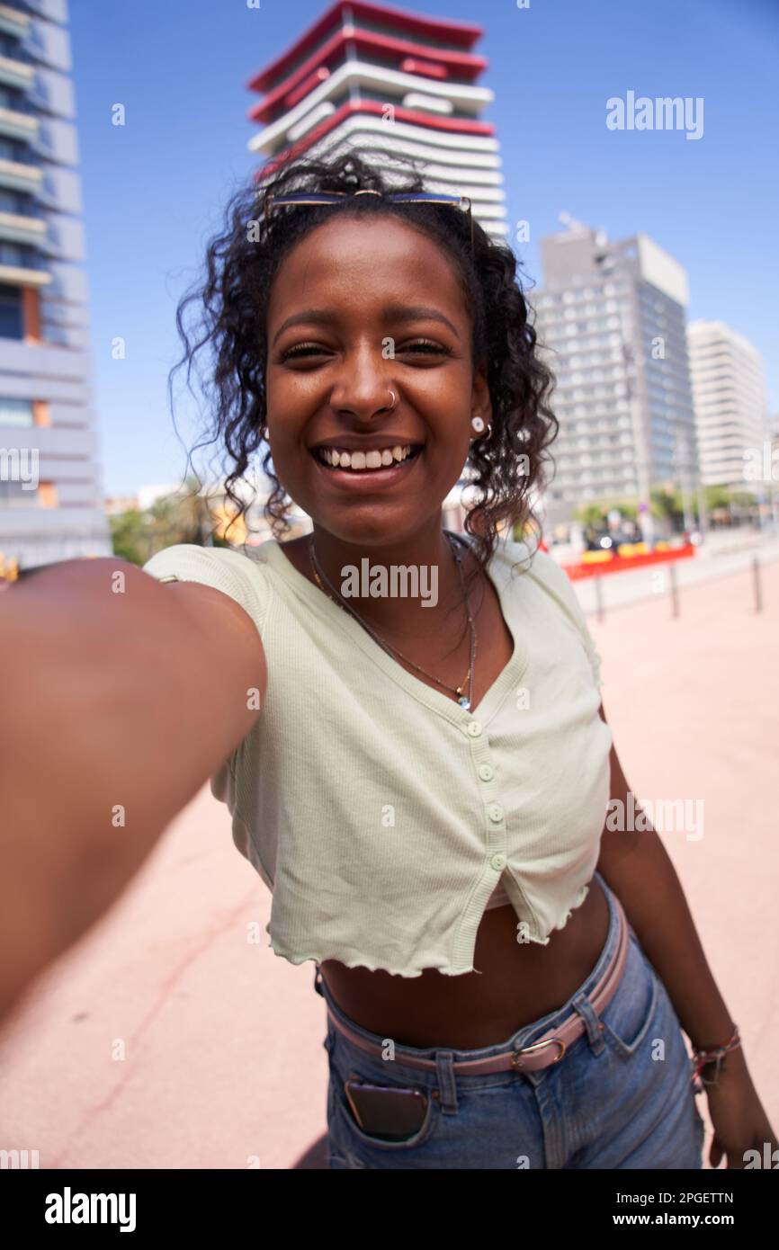 Verticale giovane ragazza africana che prende un selfie sorridente. Gente allegra in vacanza godendosi all'aperto. Foto Stock
