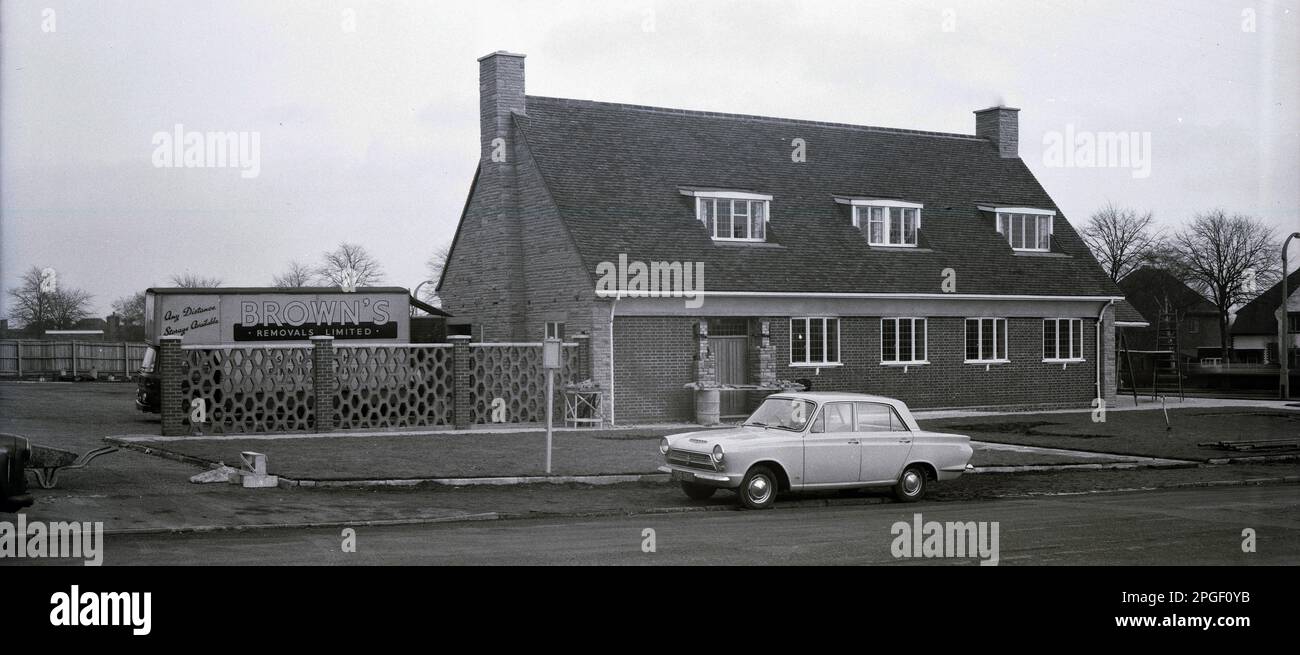 Anni '1960, storico, un nuovo edificio, un moderno edificio in stile chalet a due piani, una casa pubblica, recentemente costruita ai margini di una nuova tenuta residenziale, Birmingham, Inghilterra, Regno Unito. Una Ford Anglia berlina dell'epoca parcheggiata fuori. Un camion Browns Removals Limited nel parcheggio laterale. Foto Stock