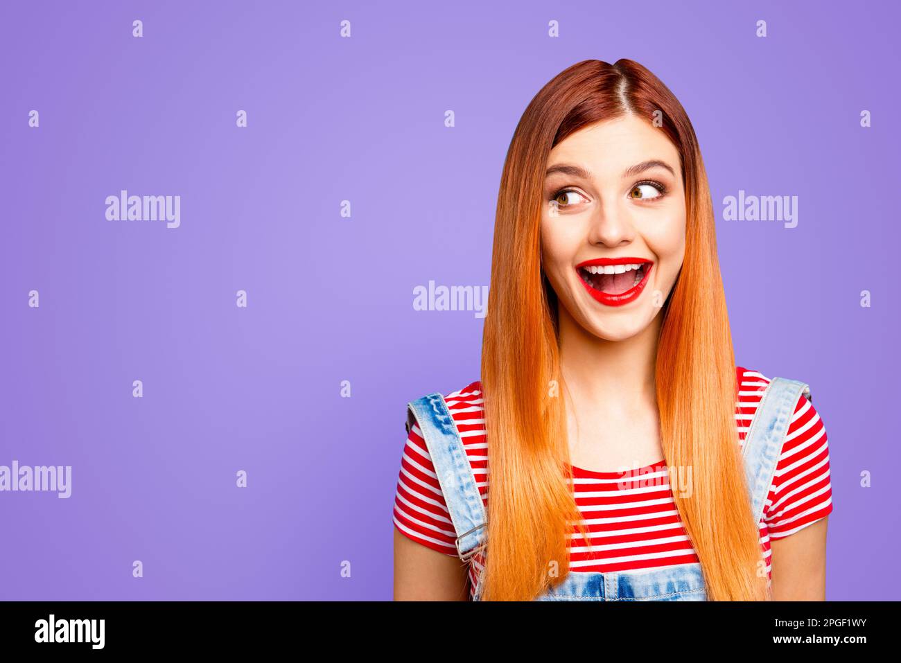 Affascinante giovane ragazza felice con le buone notizie e ora spalancata la bocca da sorpresa guarda da parte isolato su sfondo blu brillante con copia Foto Stock