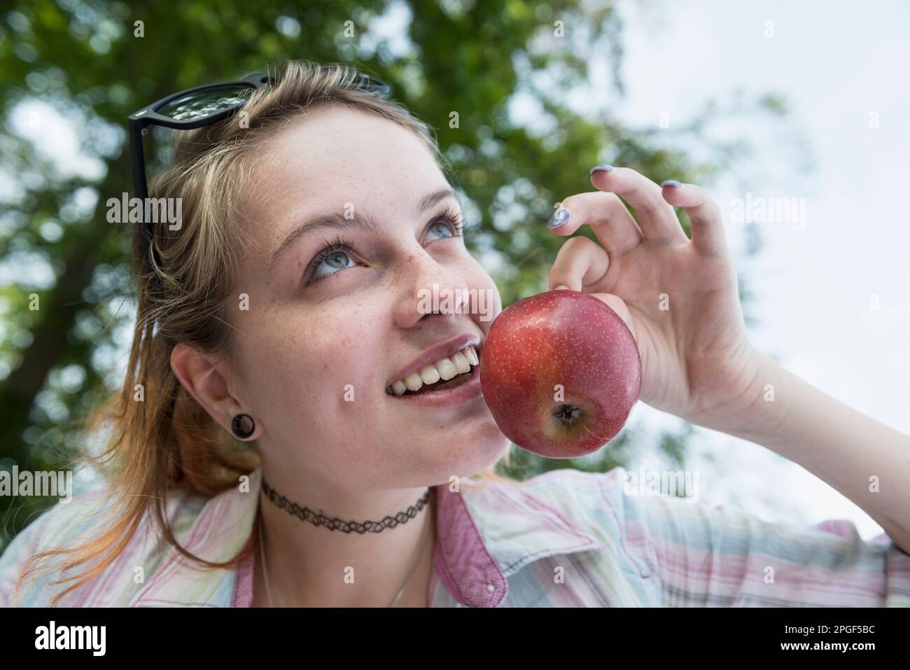 Primo piano di una giovane donna con mela rossa, Baviera, Germania Foto Stock